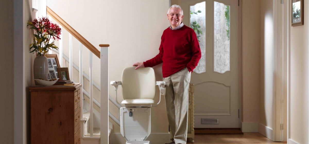 Man beside stairlift at bottom of stairs